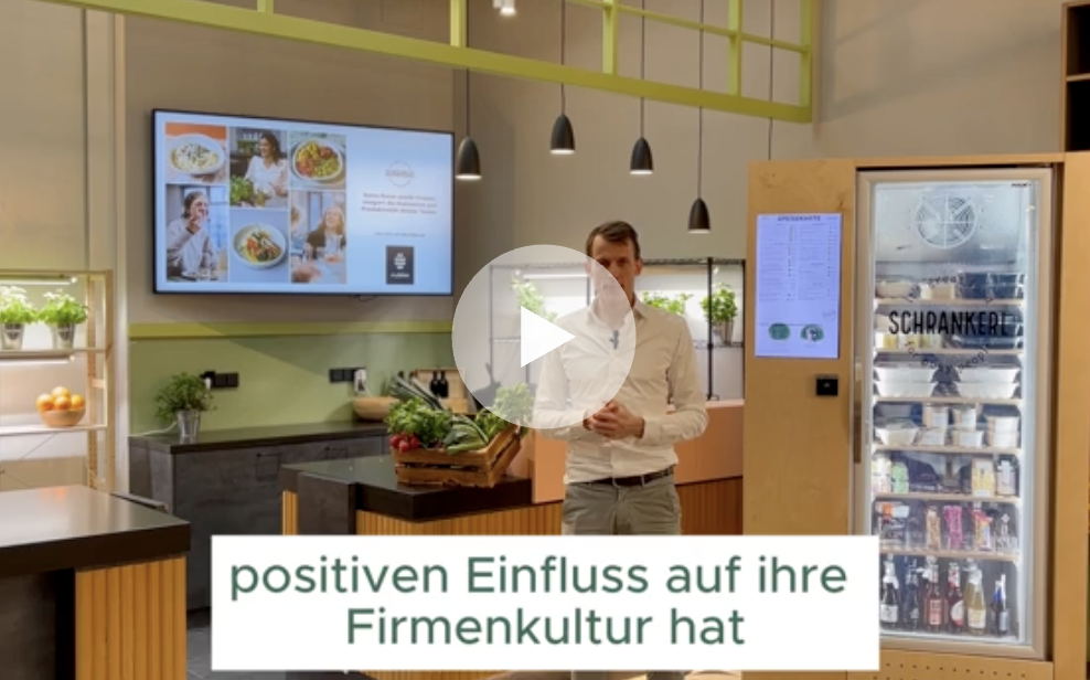 Ein Mann präsentiert die gesunde Schrankerl Mitarbeiterverpflegung in einer modernen Büroküche.