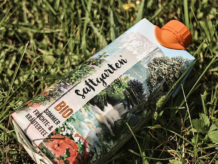 Erfrischender Bio-Tee von Schrankerl für die Mitarbeiterverpflegung liegt auf einer grünen Wiese.