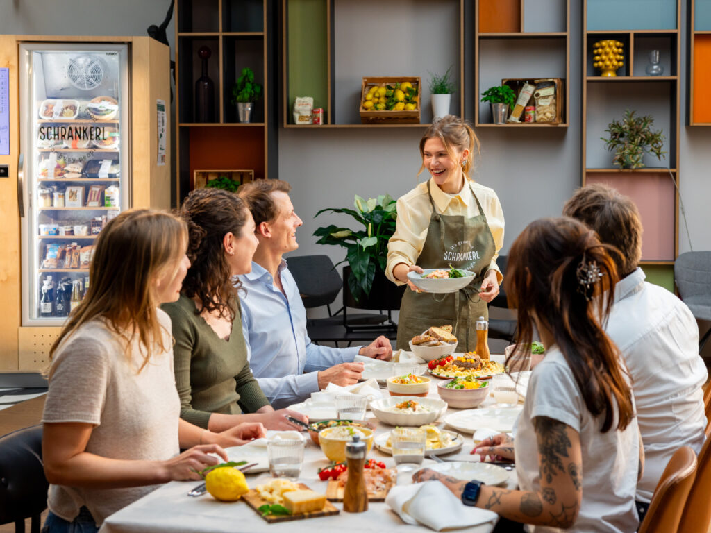 Eine lächelnde Frau serviert eine gesunde Mahlzeit für die Schrankerl Mitarbeiterverpflegung im Büro.