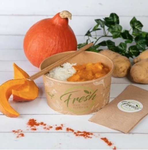 Frisch zubereitetes Kürbis-Curry mit Reis als gesunde Mitarbeiterverpflegung in einer Papierschale.