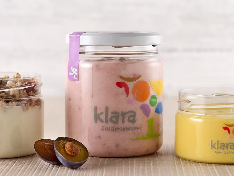 Frische Klara Fruchtsennerei Gläser mit Joghurt und Pflaumen für die gesunde Mitarbeiterverpflegung.