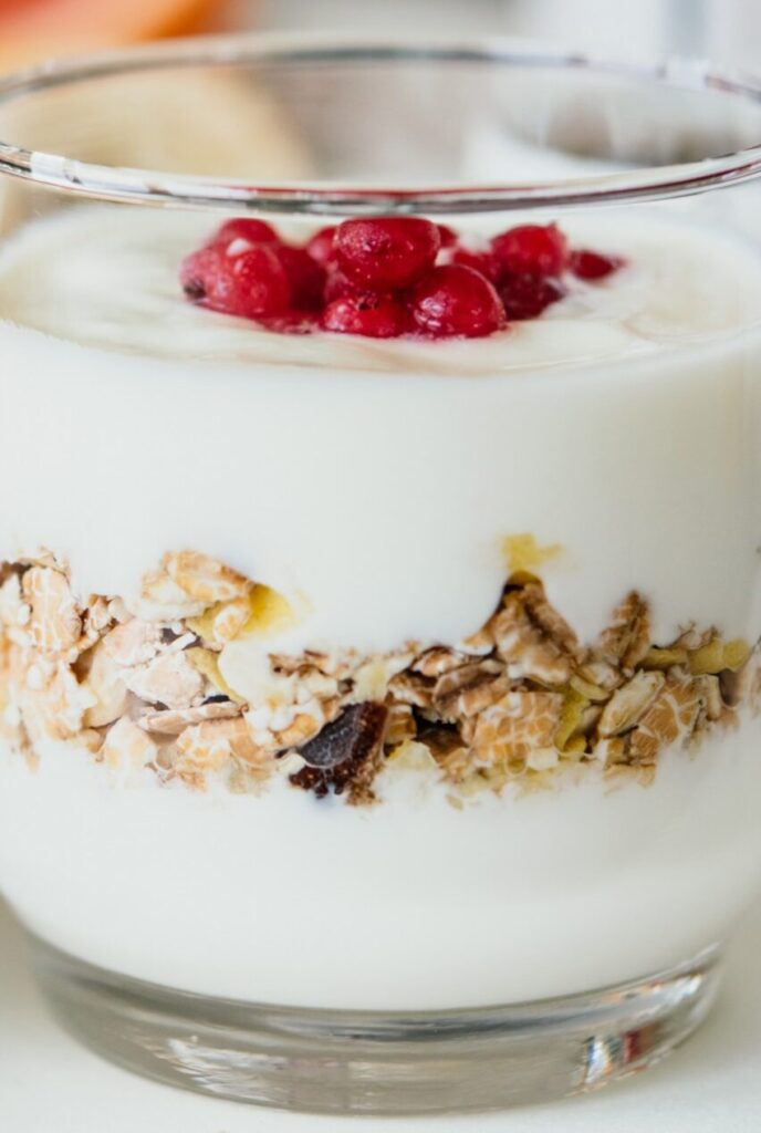 Frisches Joghurt mit Müsli und Beeren als gesunde Mitarbeiterverpflegung im Glas.