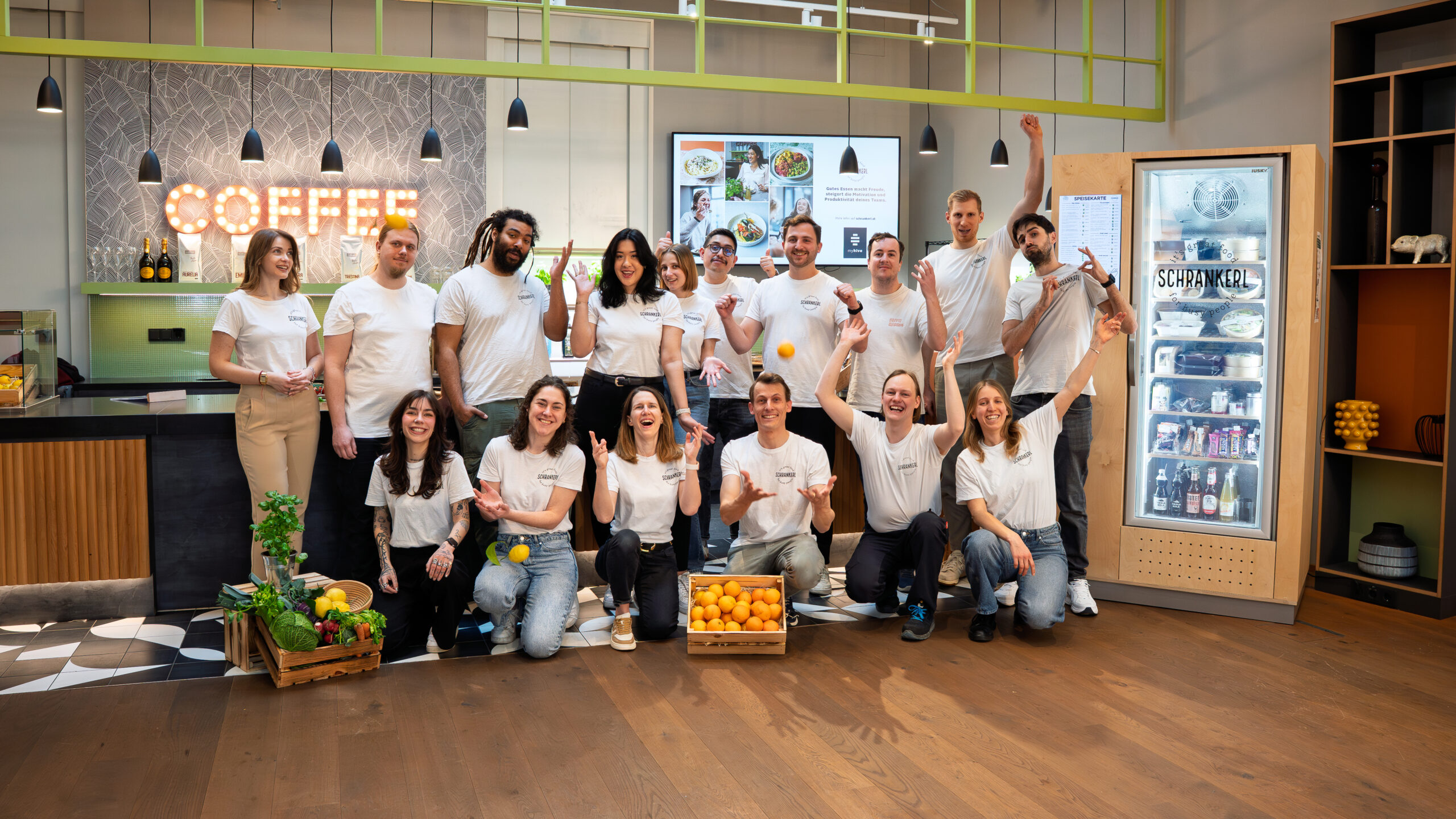 Das fröhliche Team von Schrankerl posiert gemeinsam in einer modernen Küche für Mitarbeiterverpflegung.