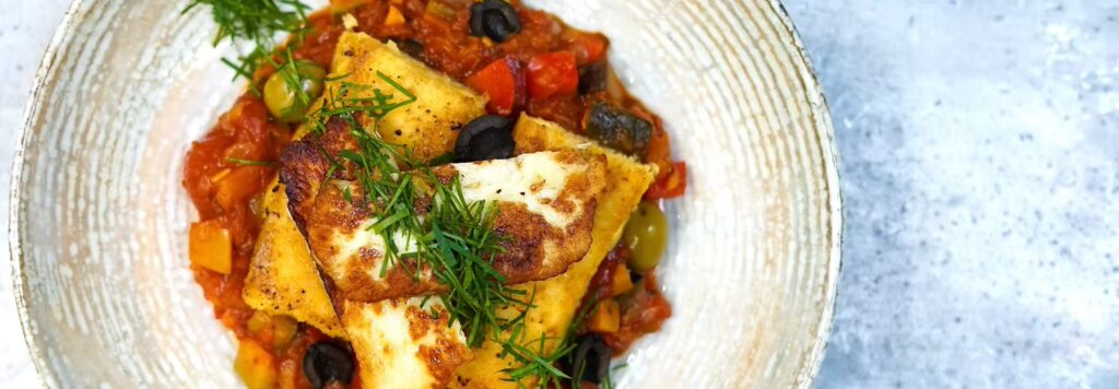 Gegrillter Halloumi auf mediterranem Gemüsebett als gesunde Schrankerl Mitarbeiterverpflegung im Büro.