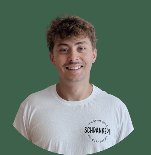 Ein lächelnder Mann im weißen Schrankerl T-Shirt für gesunde Mitarbeiterverpflegung.