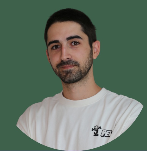 Ein lächelnder Mitarbeiter von Schrankerl im weißen T-Shirt vor grünem Hintergrund.