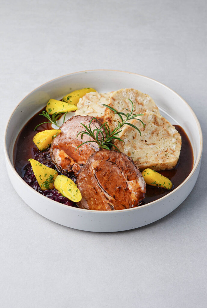 Servierter Schweinebraten mit Semmelknödeln und Rotkraut als frische Mitarbeiterverpflegung von Schrankerl.